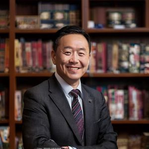 四虎影视内容总监张梅的职业形象照，面带微笑，背景为放满影视资料的书架，展现出对影视内容的深厚热情与专业积累